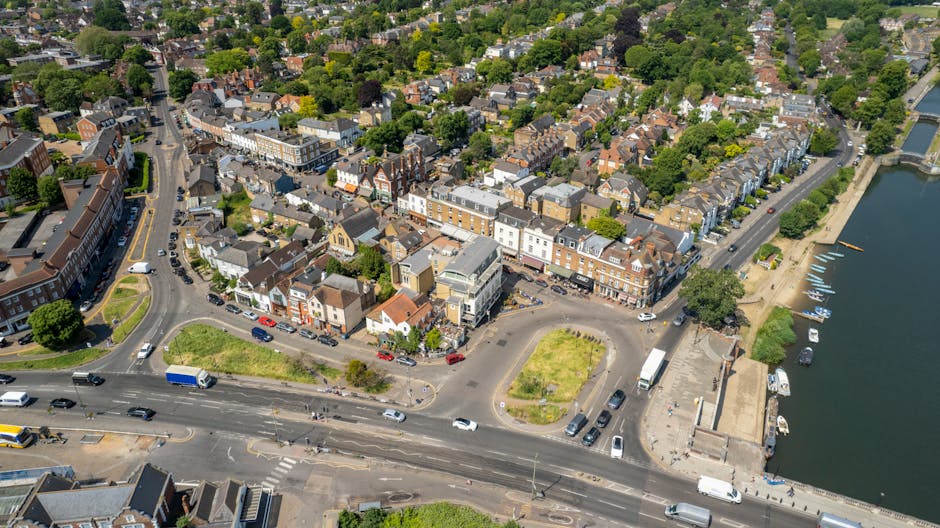 An aerial view of a circular multi-level car park with yellow safety markings along the edges and access ramps, surrounded by multi-storey residential buildings with white facades and numerous windows